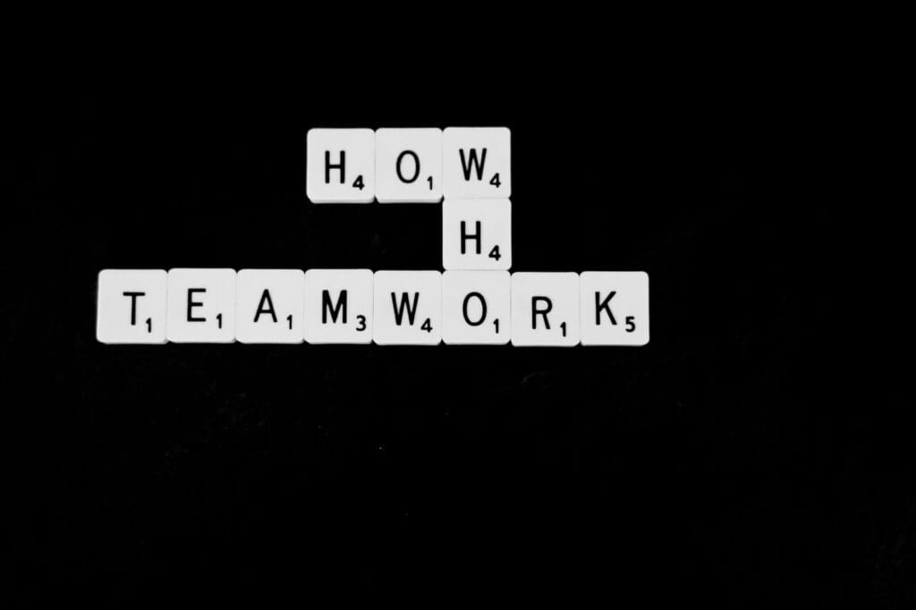 A black and white photo of scrabble tiles spelling the word teamwork