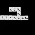 a black and white photo of scrabble tiles spelling the word teamwork