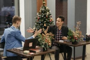 Two men in a decorated office exchanging ideas during the holiday season.